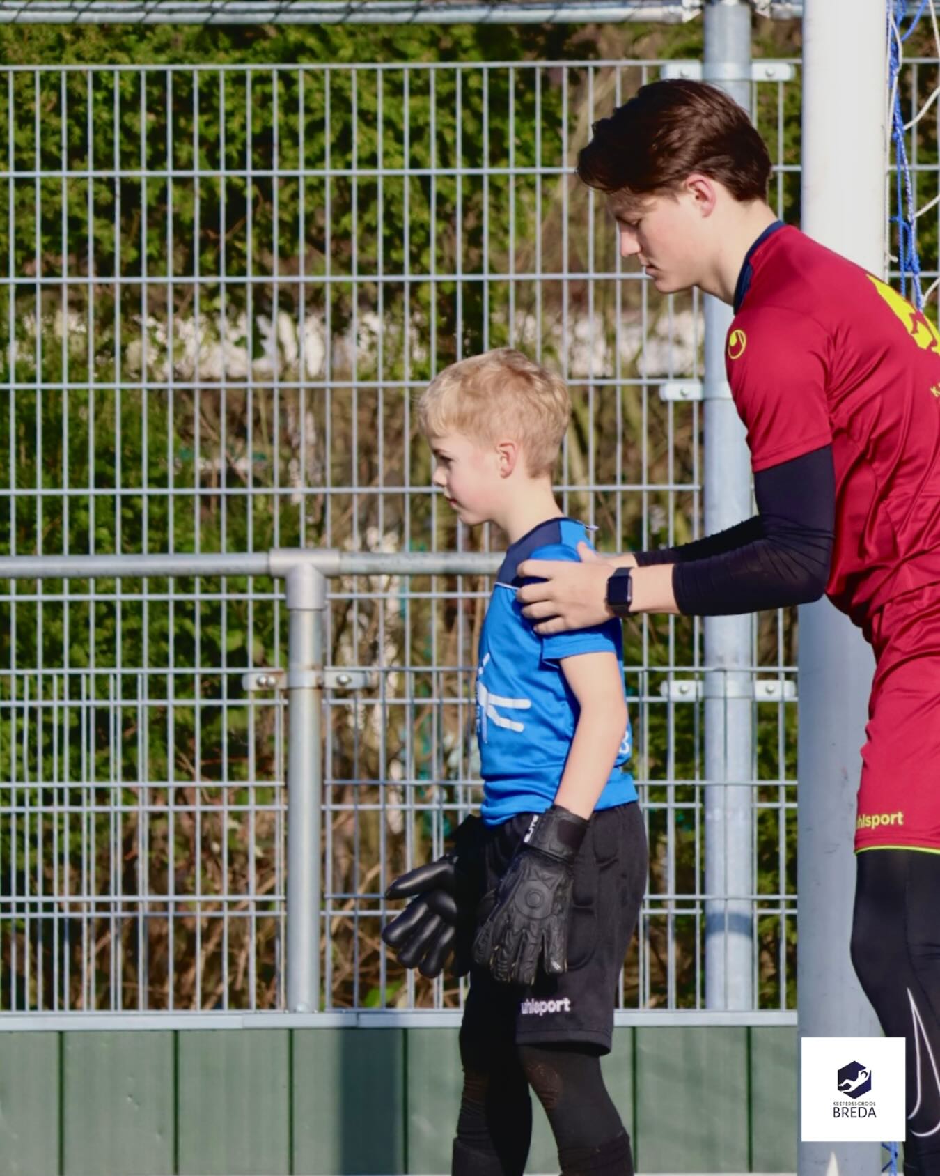Een keeperstrainer begeleidt een jonge keeper tijdens een training